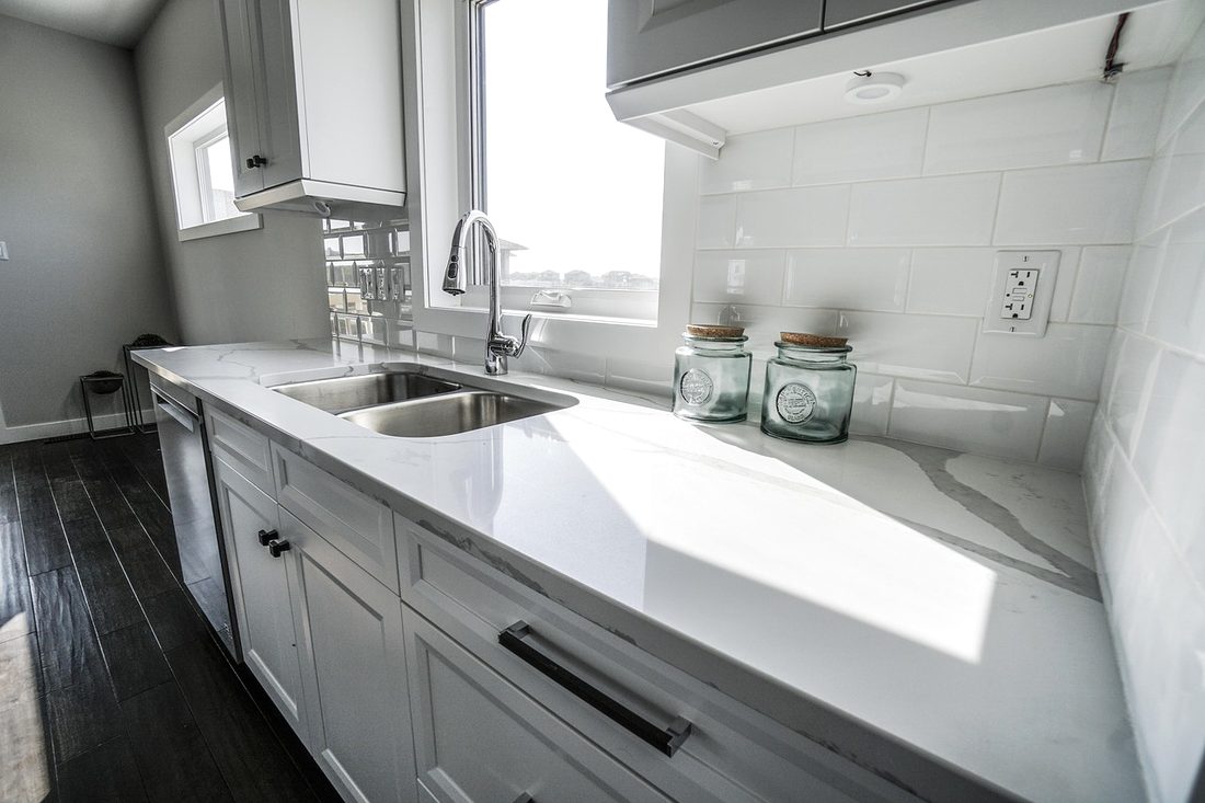 White quartz counters with an undermount sink in a sunny kitchen