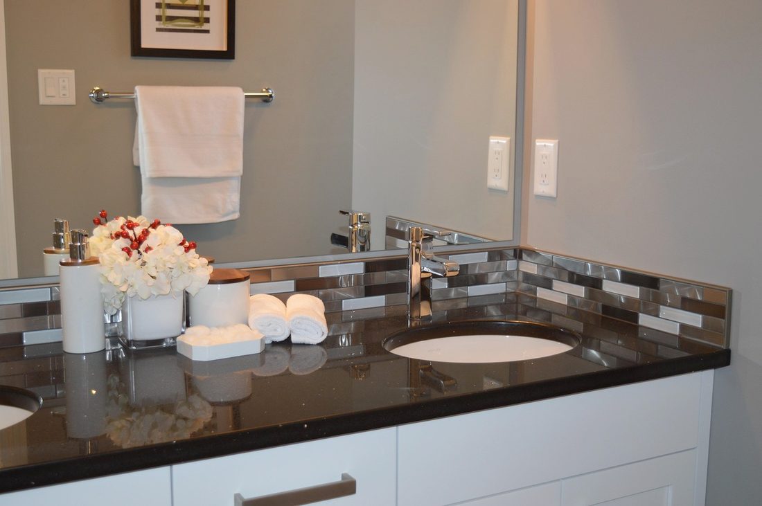 Bathroom vanity with black stone top and mosaic backsplash