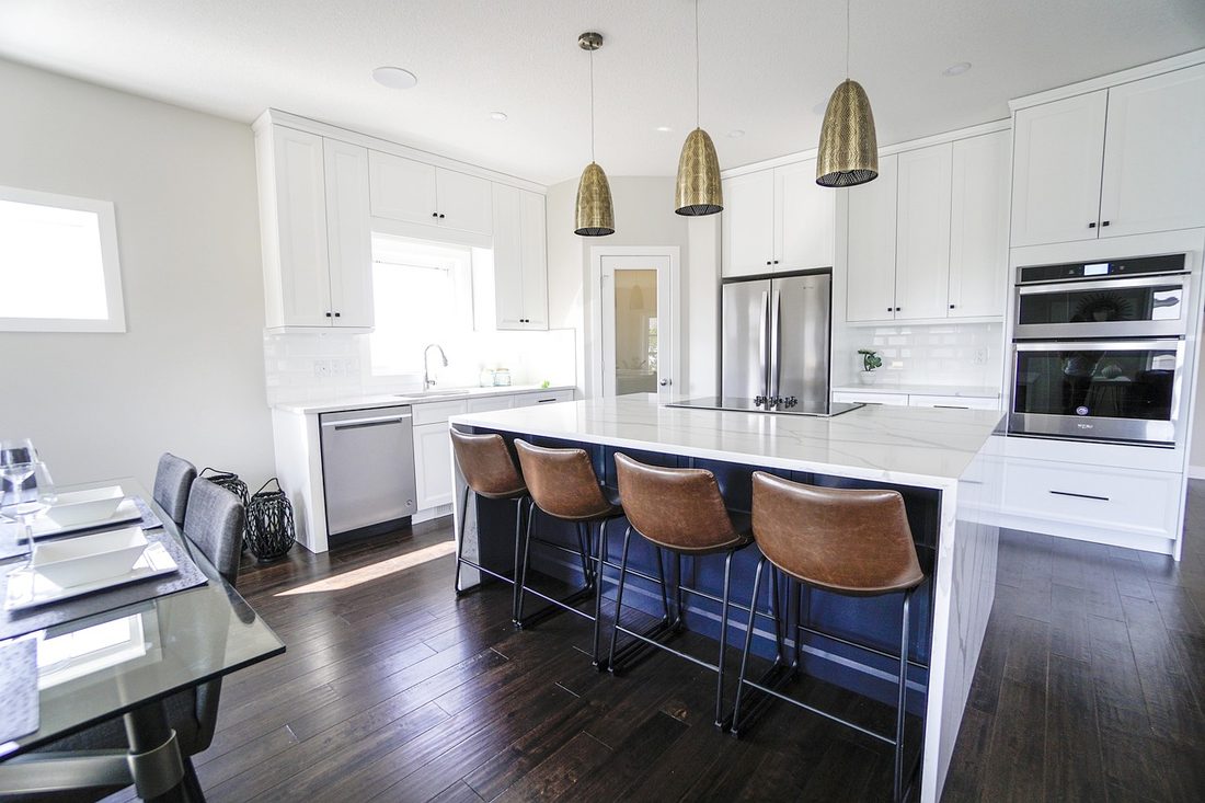 White kitchen with long quartz island and leather stools