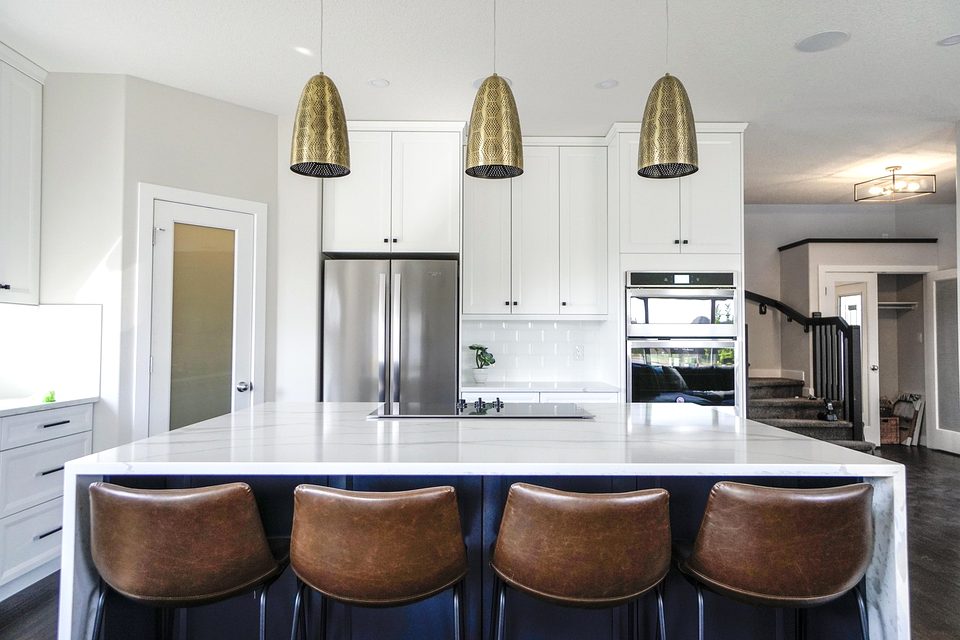 White quartz kitchen island with bar stools and brass pendants